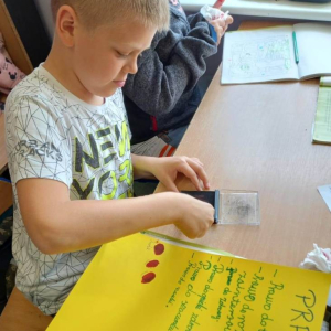pokaż obrazek - Uczeń robi odcisk kciuka na kartce