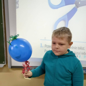 pokaż obrazek - Uczeń trzyma balon