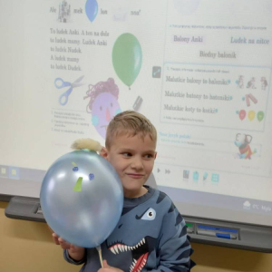pokaż obrazek - Uczeń trzyma balon