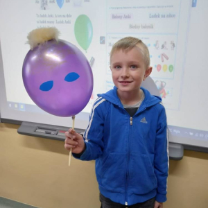 pokaż obrazek - Uczeń trzyma balon